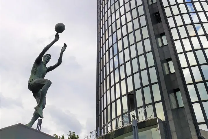 The bronze statue of basketball player Dražen Petrović in front of the curved glass Cibona tower in Zagreb